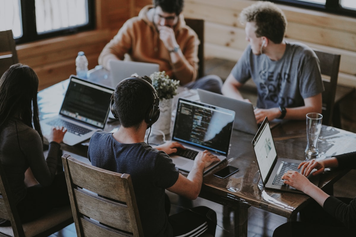 Team of developers collaborating around a table with laptops